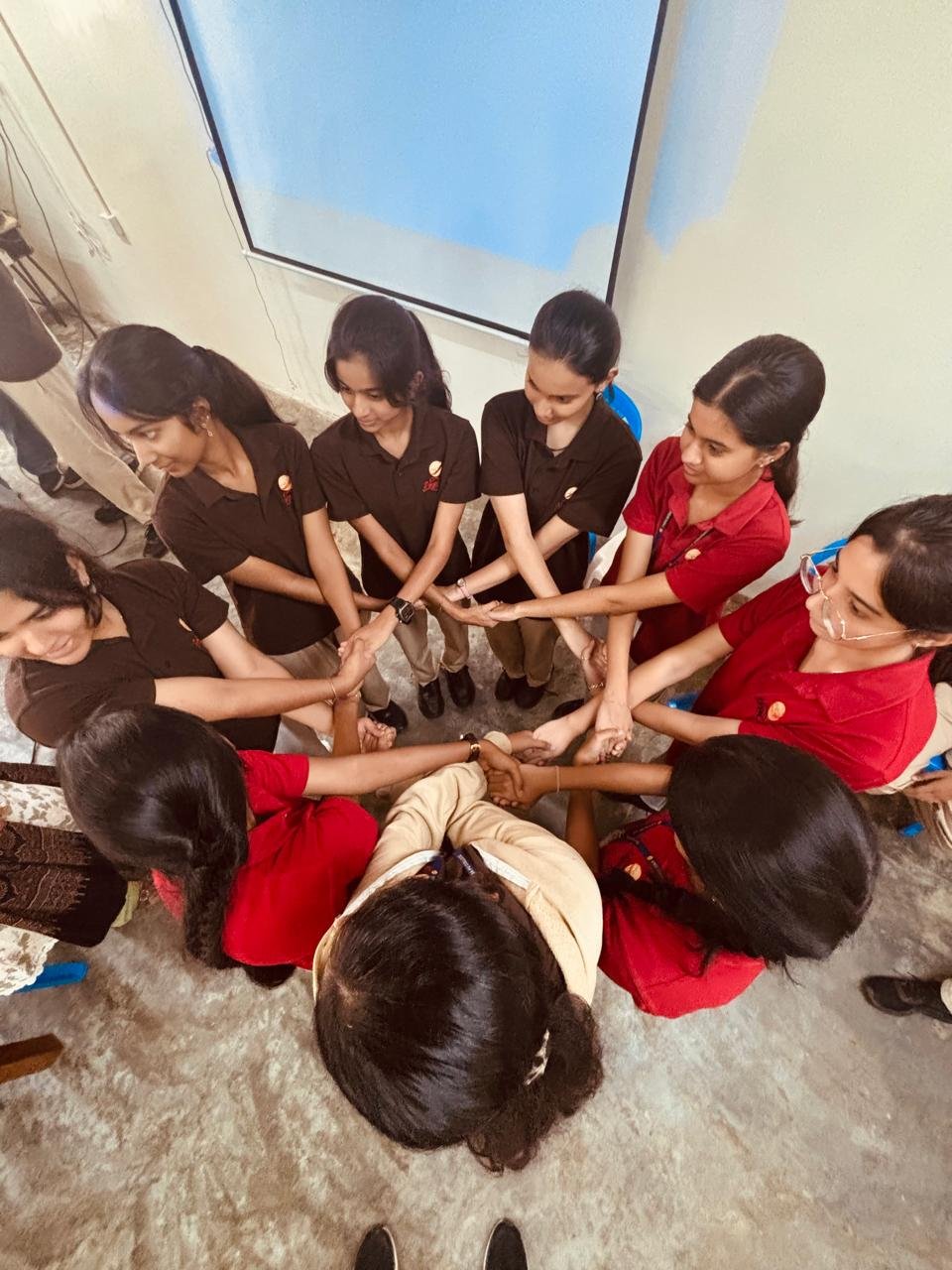 Participants standing in a circle with hands joined at the end of a team session